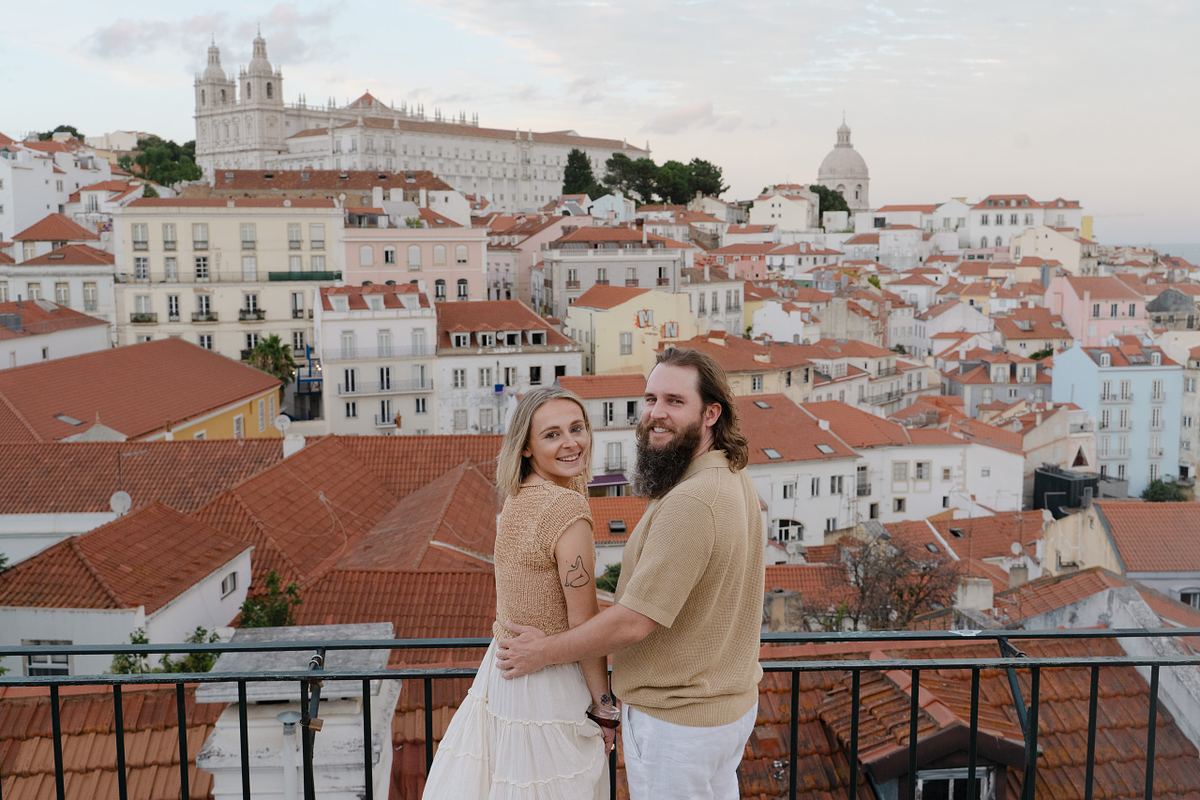 Couple sitting together at a Lisbon viewpoint overlooking the rooftops