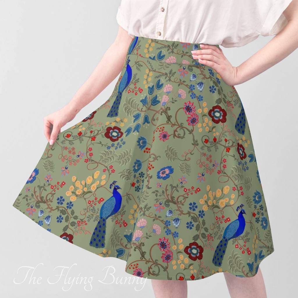 A-line skirt featuring a sage green floral pattern with blue peacocks, winding vines, and colorful folk-inspired flowers.
