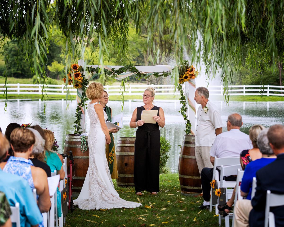 bride and groom standing underneath wedding arbour with guests looking on during an unplugged wedding ceremony
