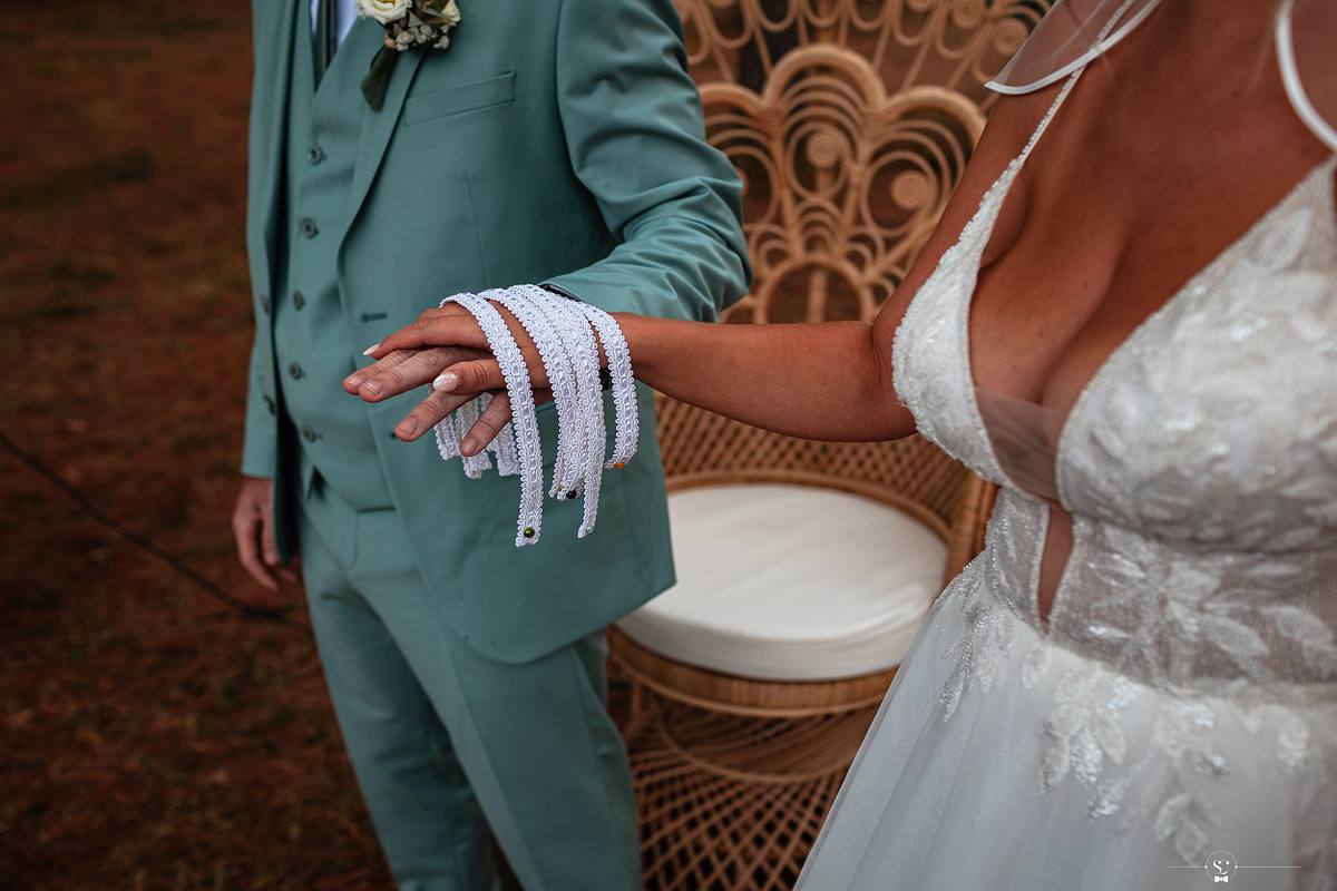 Gros plan sur les mains li&eacute;es par un ruban lors de la c&eacute;r&eacute;monie, mettant en avant les d&eacute;tails et la symbolique du lien conjugal