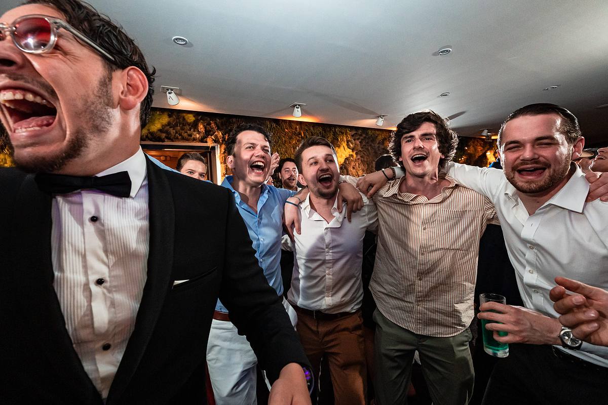 Un groupe d'invit&eacute;s en grande tenue &eacute;clate de rire, l'euphorie est palpable, une sc&egrave;ne de liesse nocturne capt&eacute;e par Sebastien CLAVEL Photographe mariage Lyon, au Pavillon du Casino Lyon vert