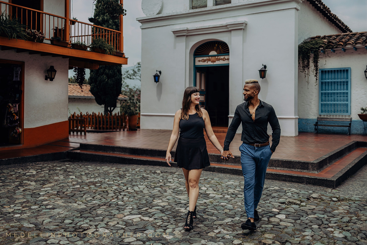 Engaged couple walking hand in hand through a colonial courtyard in Medellin