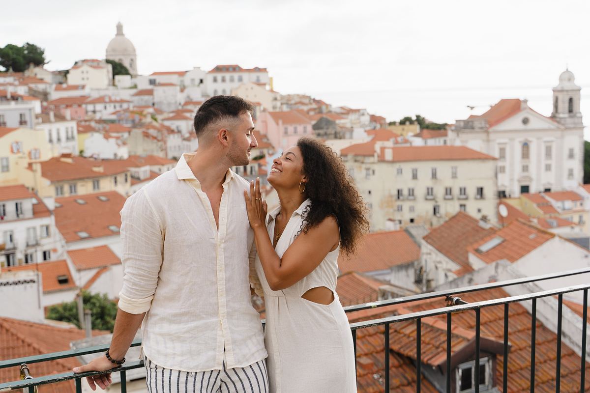 Couple kissing at a Lisbon viewpoint overlooking Alfama rooftops