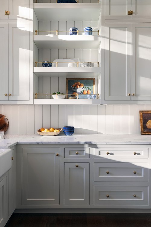 Professional interior photography of a high-end mansion kitchen in St. Johns County, Florida, featuring custom white cabinetry, a large marble island, and modern pendant lighting.