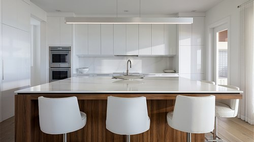 Professional photography of a minimalist coastal kitchen island and modern bar lighting in Ponte Vedra Beach, Florida.