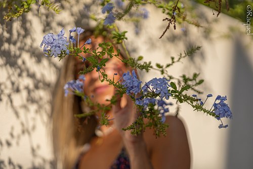 Portrait lifestyle d’une femme derrière des fleurs bleues à Carqueiranne, réalisé par Raquel Gouiffes, photographe portrait dans le Var.