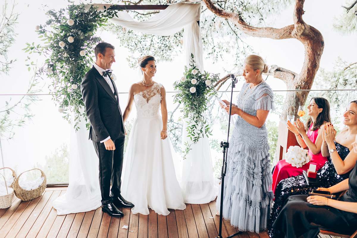Bride and groom smiling beneath the floral ceremony arch in Göcek