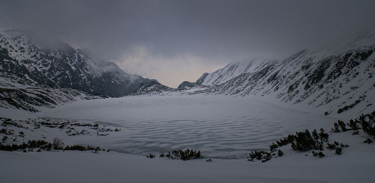 Frozen Morskie Oko lake surrounded by snow-covered peaks in the Tatra Mountains, Poland.