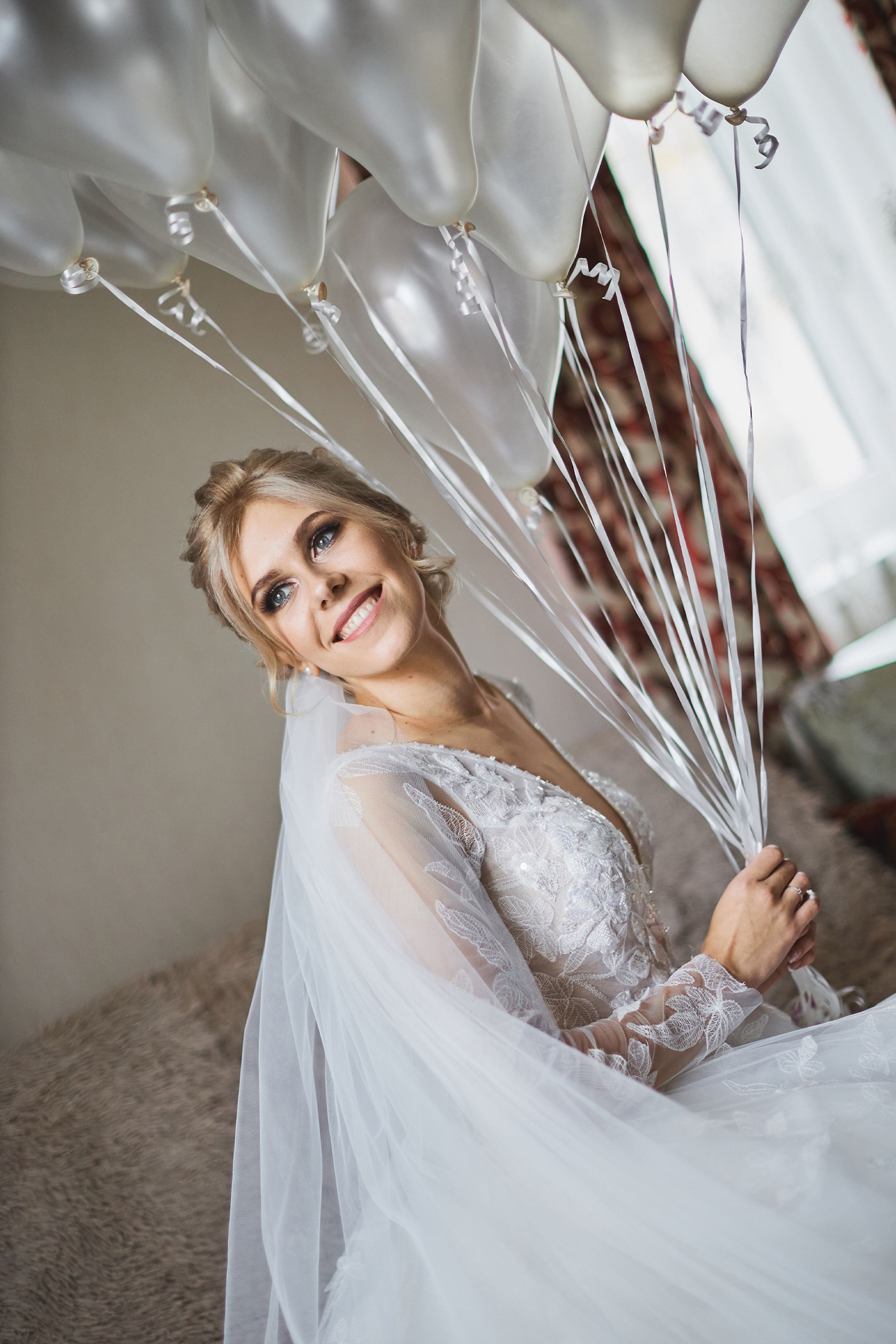 Bride holding white balloons during her wedding day