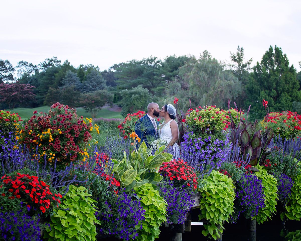 award winning flower covered bridge at baywood with couple standing in the center