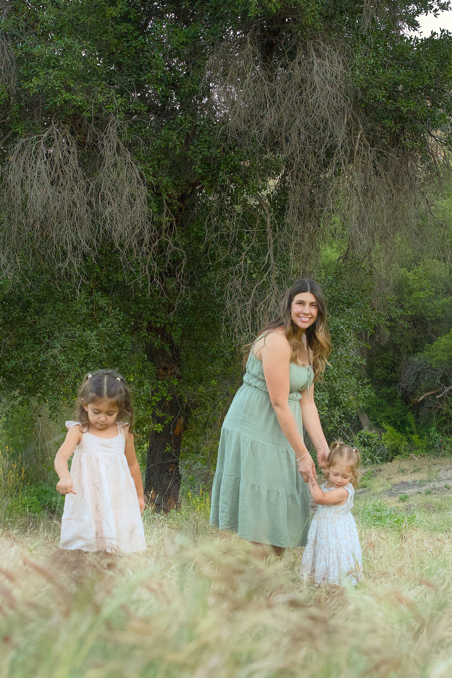 Mother with two girls in a green outdoor portrait.