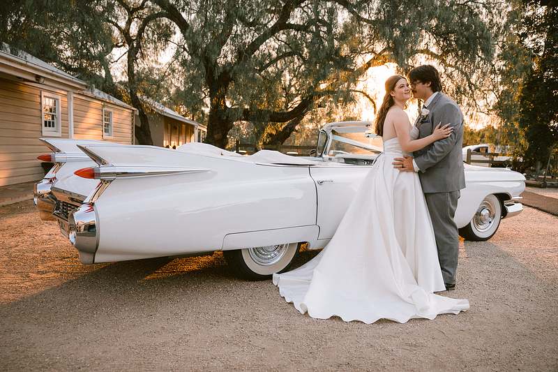 Sunset wedding photo of bride and groom in front of a vintage car at Gledswood Homestead and Winery