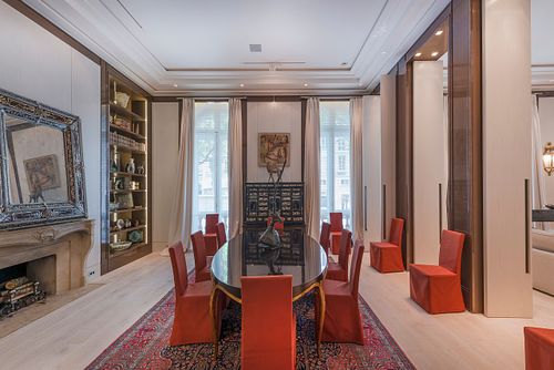Salle à manger haussmannienne à Saint-Germain-des-Prés avec table ovale, chaises rouges et grande cheminée ancienne. Photographie d'architecture intérieure et décoration par Nicolas Karadimos.