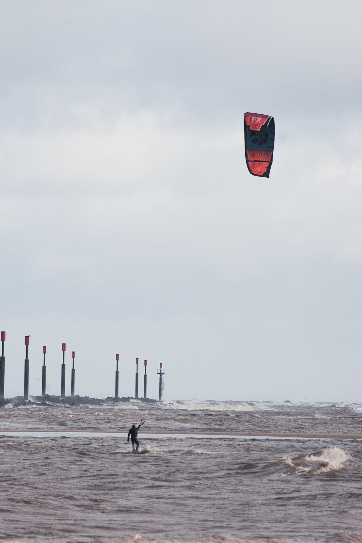 Kitesurfer riding the waves along the Norfolk coast on a windy day.
