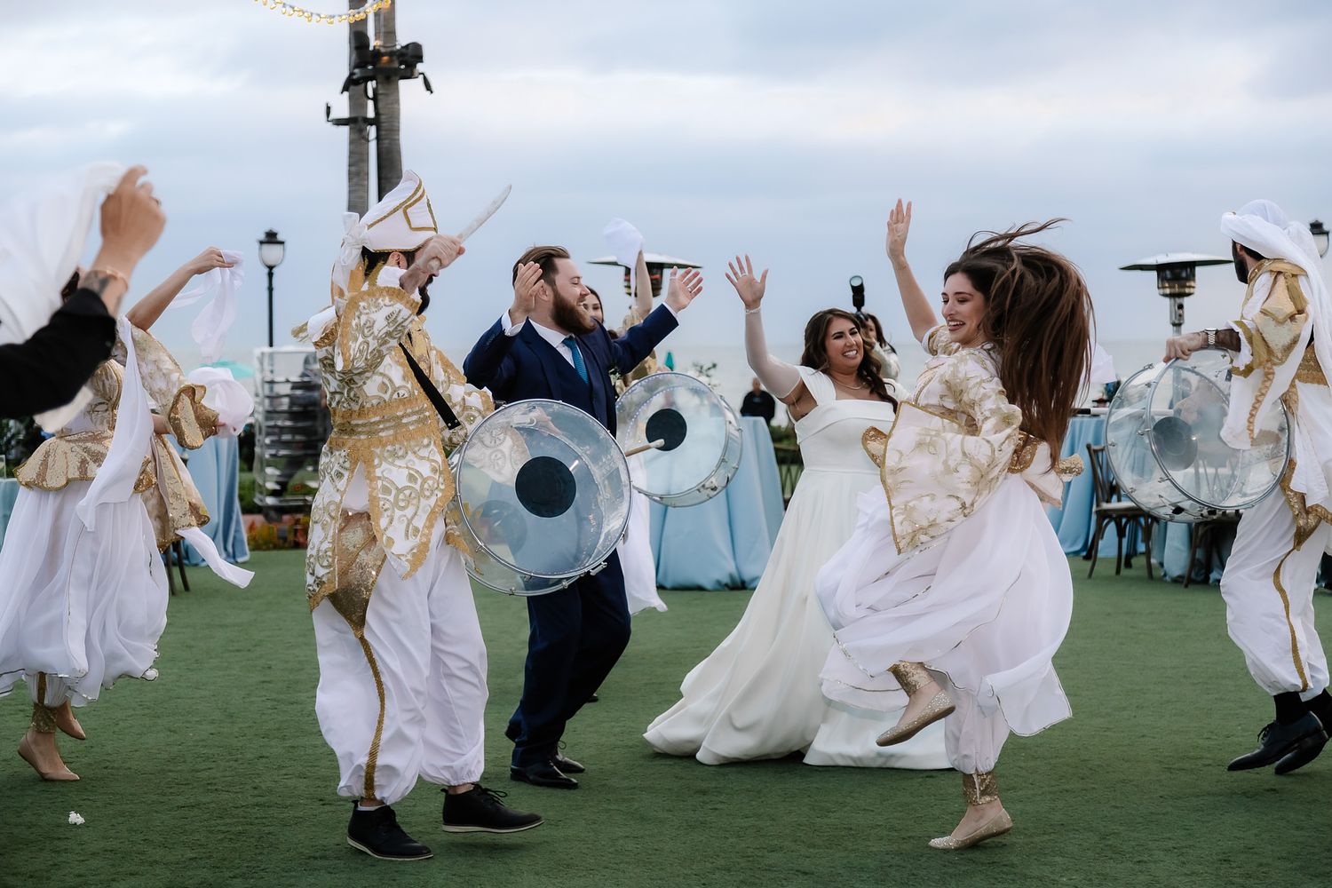 Bride and groom celebrating with traditional dancers during their Hotel del Coronado wedding in San Diego