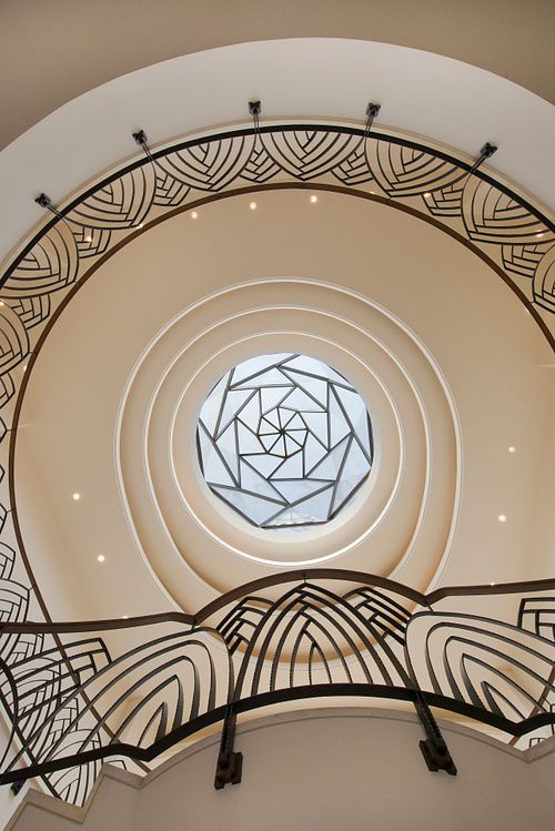 Détail d’un plafond Art Déco avec rosace géométrique centrale et balustrade sculptée. Photographie d’architecture intérieure par Nicolas Karadimos.