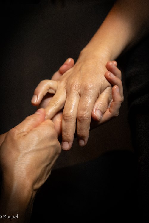 Les mains de la praticienne en contact avec celles de la cliente pendant un soin bien-être.
