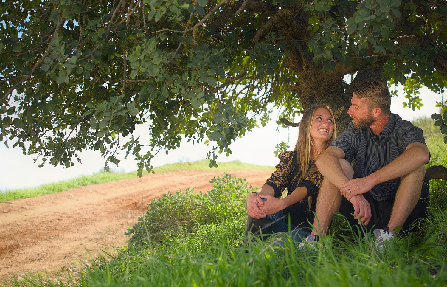 Couple seated together under a tree during a quiet portrait session.