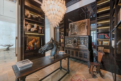 Bibliothèque et cabinet de curiosités à Saint-Germain-des-Prés avec lustre en verre sculptural, tête de cheval en bronze et meubles anciens. Photographie d'architecture intérieure par Nicolas Karadimos.