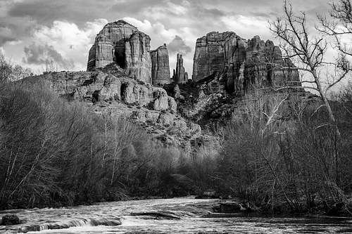 A powerful horizontal black and white fine art landscape of Castle Rock in Sedona, Arizona, during sunset, highlighting the long shadows and dramatic textures of the canyon rocks.