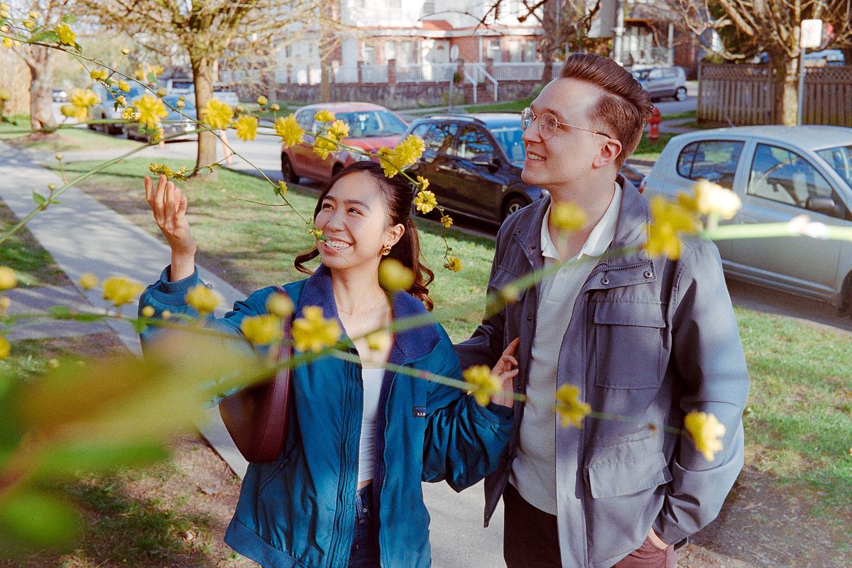 a 35mm film shot of a couple stopping to look at some flowers on a tree