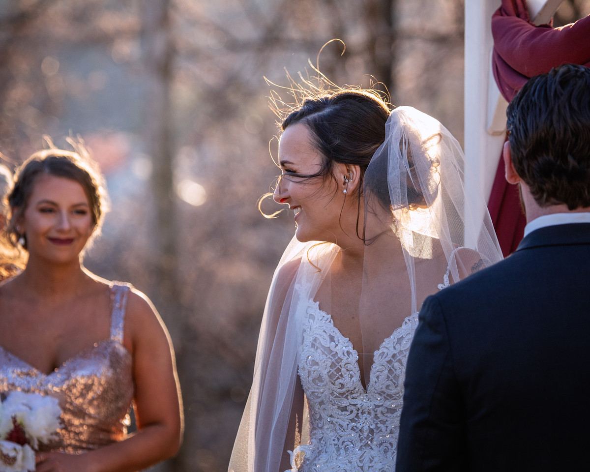 Winter wedding during sunset hours the bride and groom during the ceremony, the bride is smiling at her bridesmaids