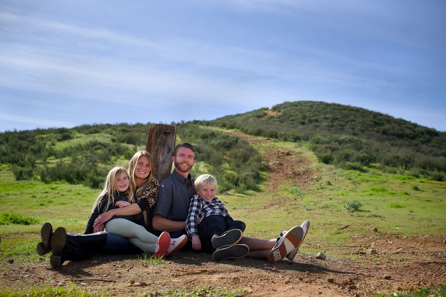 Family seated together in a grassy hillside portrait.