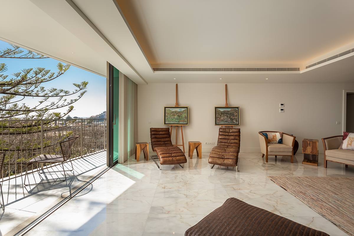 Sala de apartamento de luxo no Legacy Residences Cascais com liga&ccedil;&atilde;o &agrave; varanda e vista mar