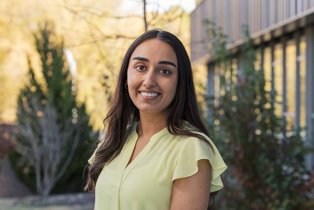 A researcher poses for a headshot in front of the Downtown Durham (NC) Public Library