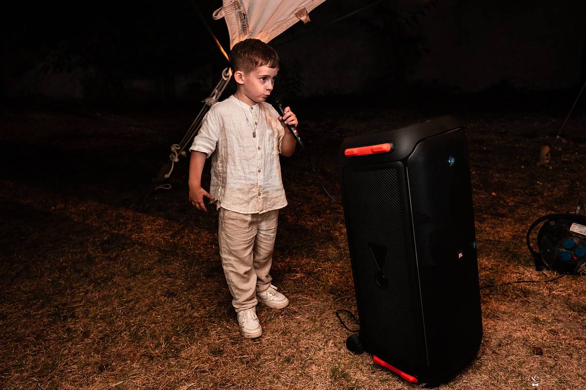 Fils de la mari&eacute;e en train de chanter pendant la Soir&eacute;e sous la tente apr&egrave;s la C&eacute;r&eacute;monie La&iuml;que sous le soleil de Sommi&egrave;res. Mariage N&icirc;mes - Occitanie. Sebastien Clavel Photographe Mariage Lyon
