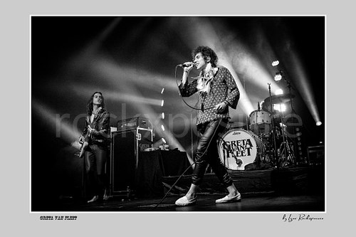 Horizontal black and white image of Greta Van Fleet members Sam Kiszka and Josh Kiszka performing on stage