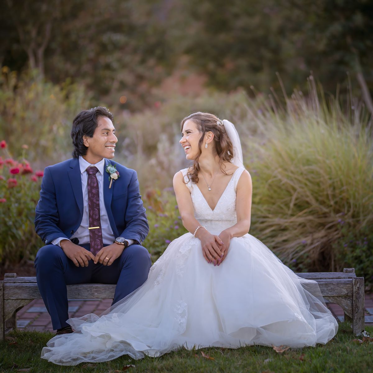 bride and groom sitting on a low bench, relaxed and natural and laughing by windsweptphotodesign