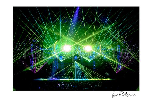 Horizontal color image of Trans Siberian Orchestra performing on stage beneath green and blue laser lights