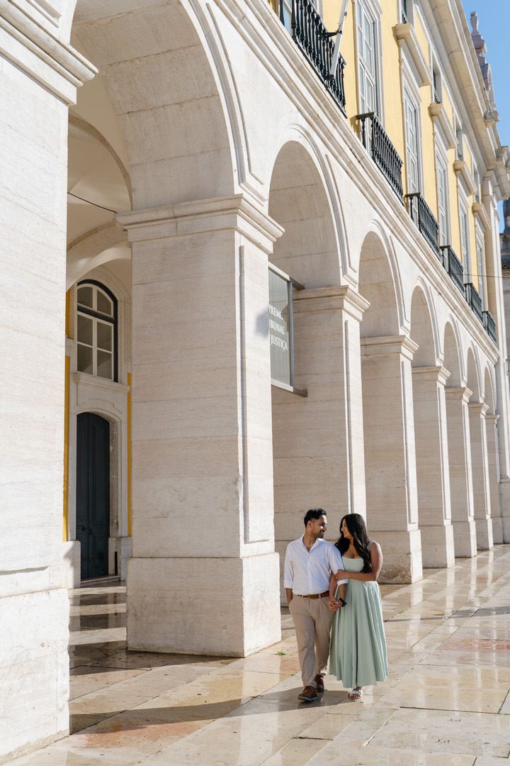 Couple walking beneath the arcades of Pra&ccedil;a do Com&eacute;rcio in Lisbon