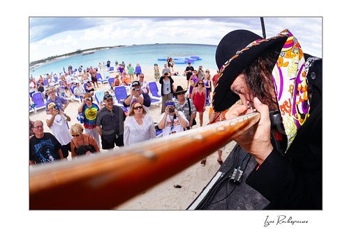 Horizontal color image of Randy Hansen in an extreme outdoor close-up on a beach stage with his guitar neck leading toward a crowd of fans