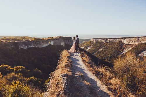 Bride and groom walking in mountains at sunset. Around the stunn