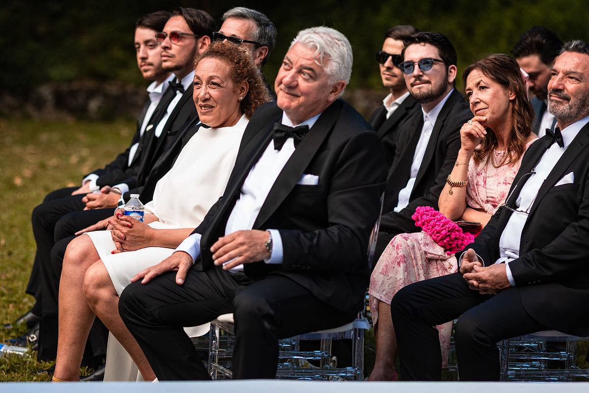 Invit&eacute;s &eacute;l&eacute;gants en tenue de c&eacute;r&eacute;monie, partageant joie et anticipation sous les arbres du Pavillon Casino Lyon Vert