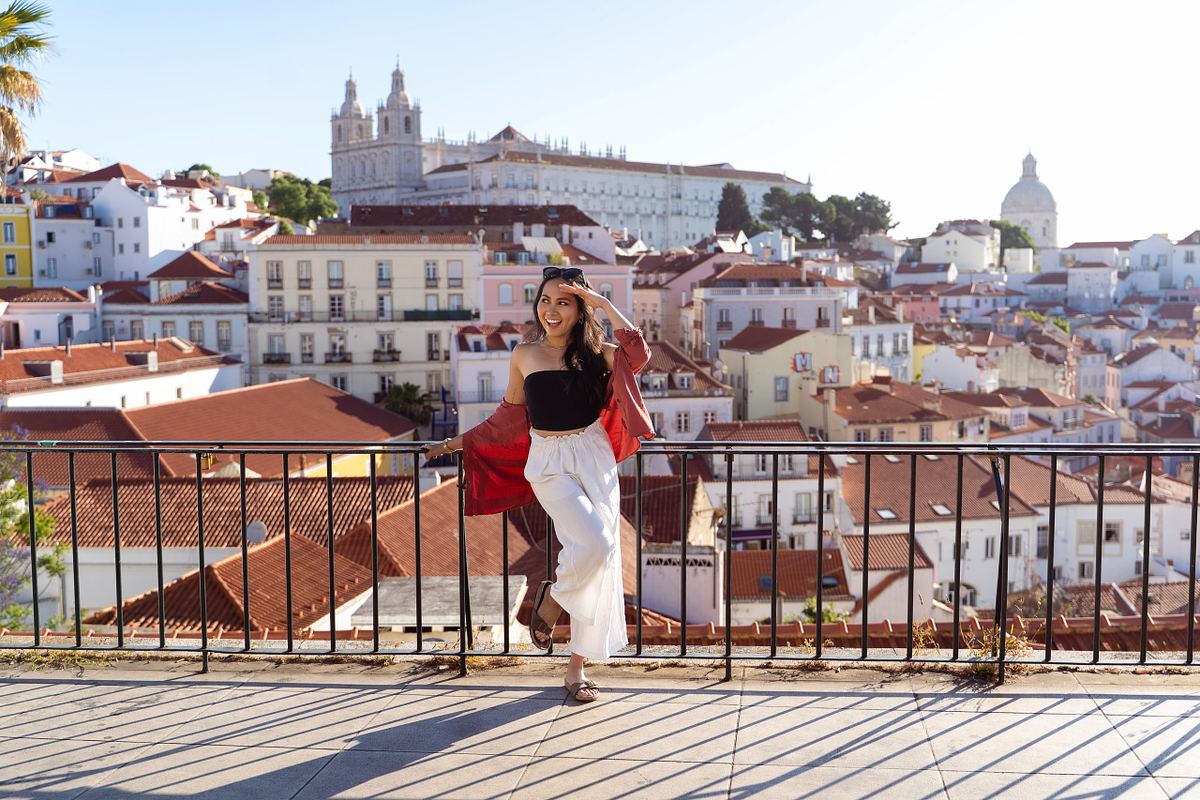 Solo traveler overlooking Lisbon rooftops from the viewpoint of Portas do Sol in Alfama