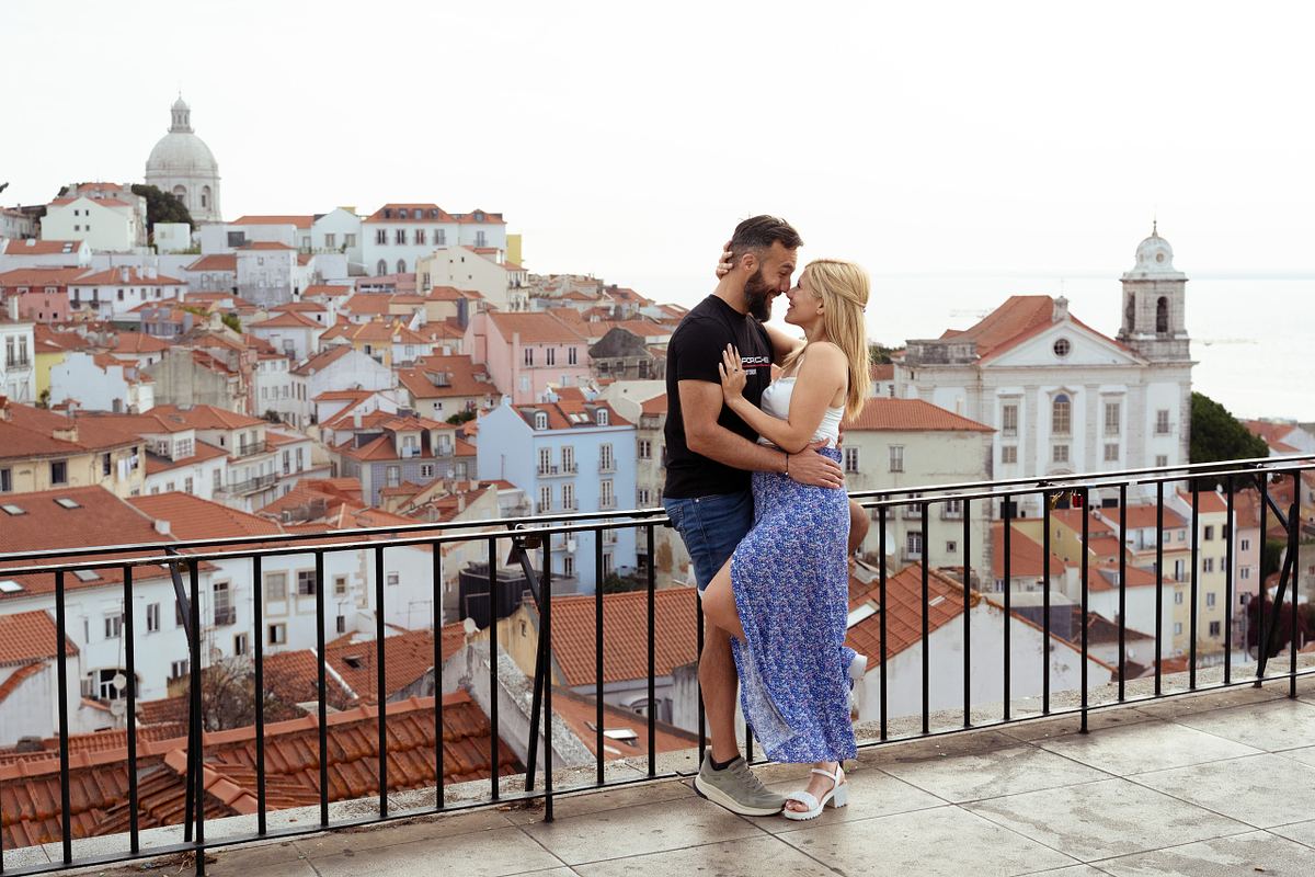 Couple embracing at a Lisbon viewpoint overlooking Alfama