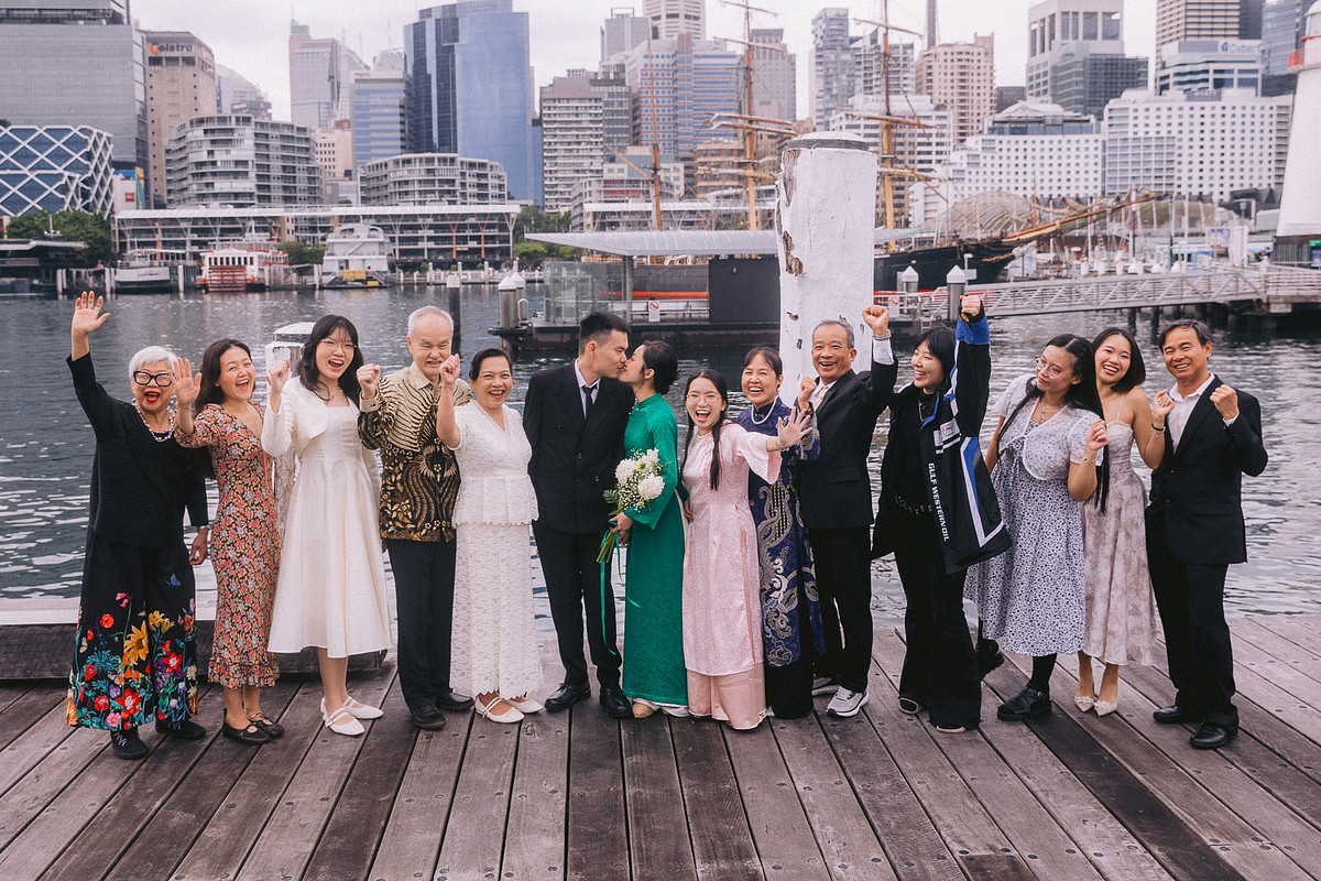 bride and groom sharing a kiss during the group photo with family outside Pyrmont Wedding Registry