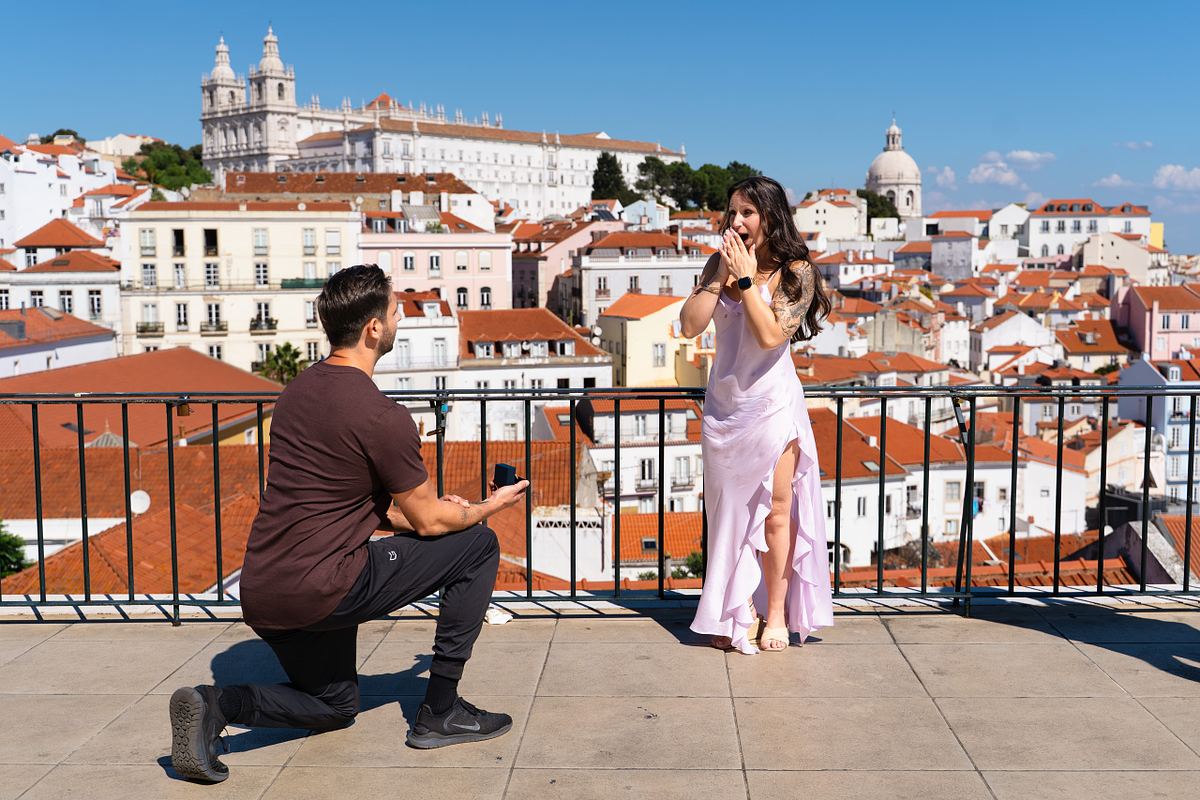 Woman reacting with joy to a surprise proposal at an Alfama viewpoint