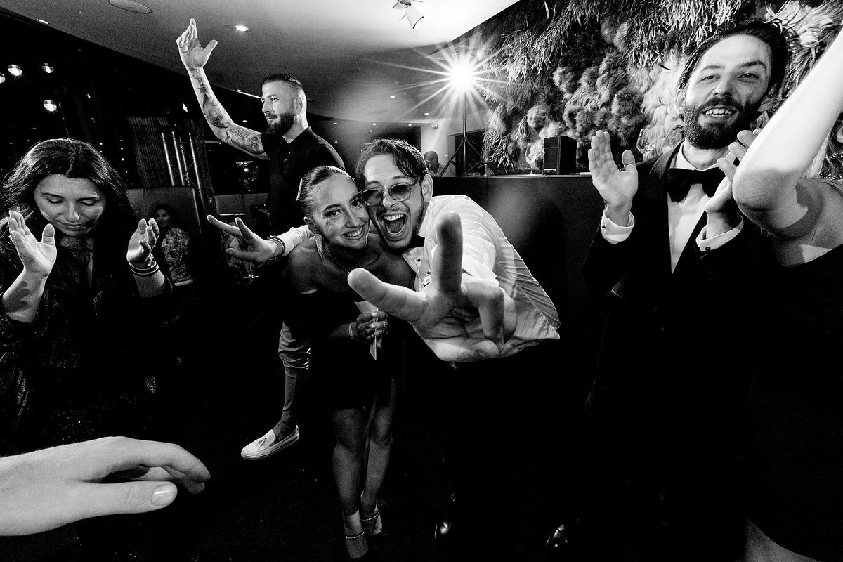 Deux invit&eacute;s se d&eacute;hanchent devant l'objectif, entour&eacute;s d'amis en plein fou rire, un moment de pur bonheur en noir et blanc saisi par Sebastien CLAVEL Photographe mariage Lyon &agrave; l'H&ocirc;tel Pavillon du Casino Lyon vert