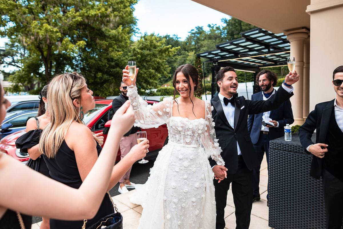 Les nouveaux mari&eacute;s l&egrave;vent leurs verres en c&eacute;l&eacute;bration, entour&eacute;s d'amis qui partagent leur joie, un instant joyeux et plein de vie captur&eacute; par Sebastien CLAVEL Photographe mariage Lyon