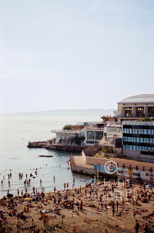 Photographie argentique de la plage des Prophètes avec baigneurs et vue sur le Cercle des Nageurs de Marseille, par Dimitri Eteni