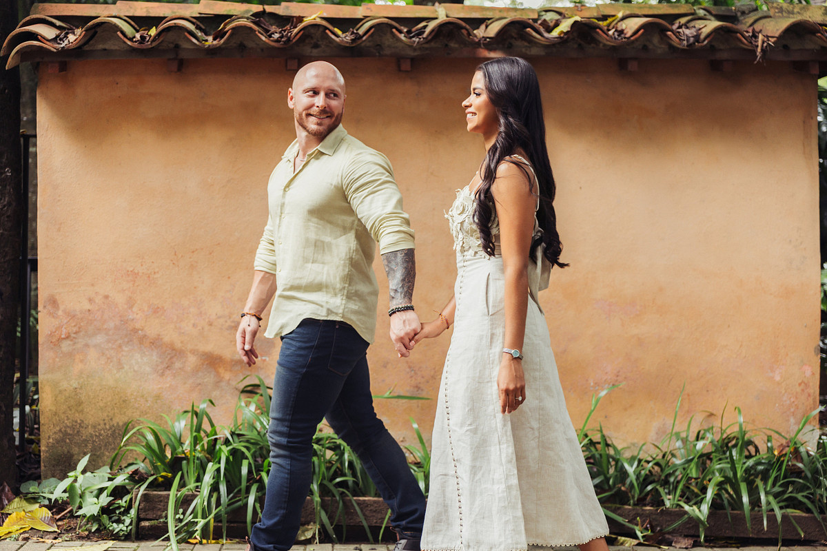 Bride to be and her fiance walking beside a warm ochre garden wall in Medellin