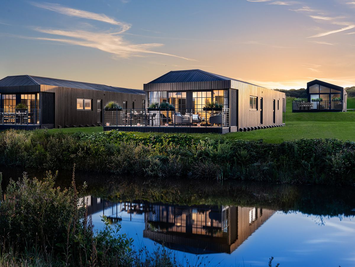 A holiday lodge in by a lake in Cornwall at dusk.