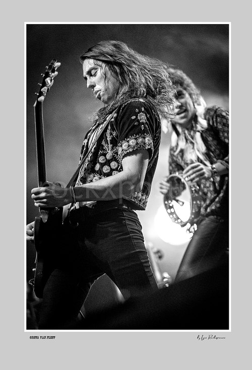 Vertical black and white image of Greta Van Fleet members Sam Kiszka and Josh Kiszka performing on stage