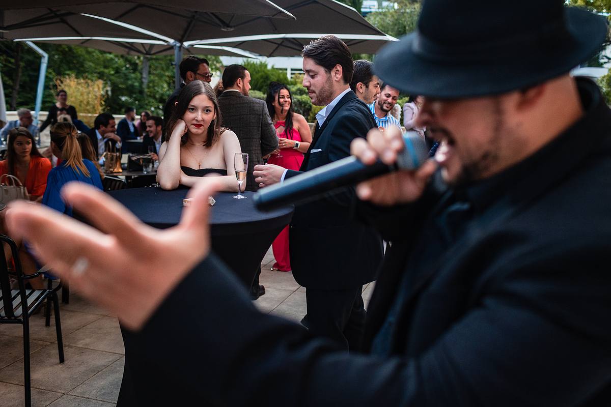 La soir&eacute;e s'anime avec le chanteur du 'Groupe Love' implorant la foule avec son micro, sa pr&eacute;sence sc&eacute;nique contrastant avec la tranquillit&eacute; des invit&eacute;s, dans une sc&egrave;ne saisie par Sebastien CLAVEL Photographe mariage Lyon