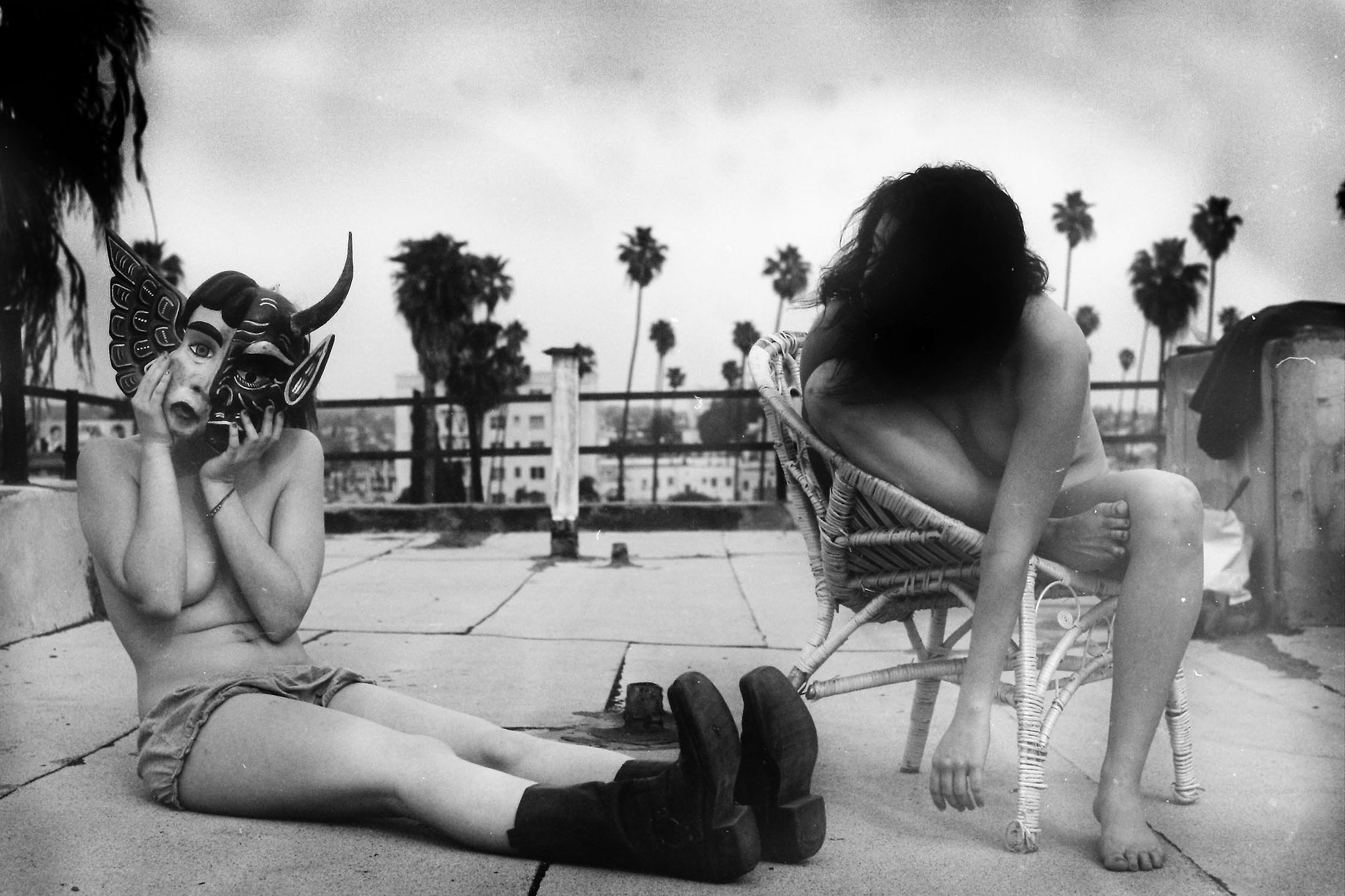 A masked and faceless woman sit on rooftop by copenhagen fine art photographer