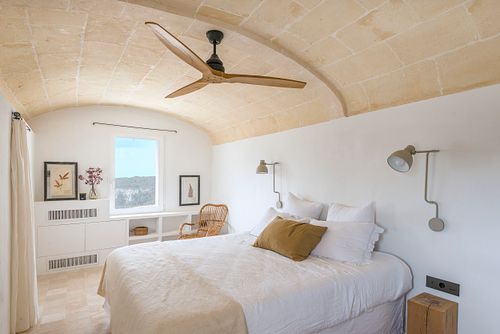 Chambre voûtée en pierre avec lit double et ventilateur de plafond dans la finca Son Fonoll à Minorque. Photographie par Nicolas Karadimos.